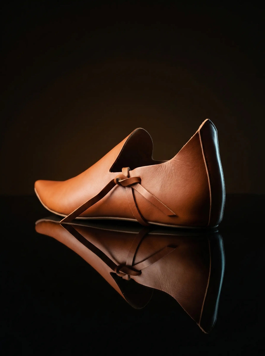 Leather thong tie closure on Noirtide natural tan poulaine shoe — archaeologically documented toggle fastening method