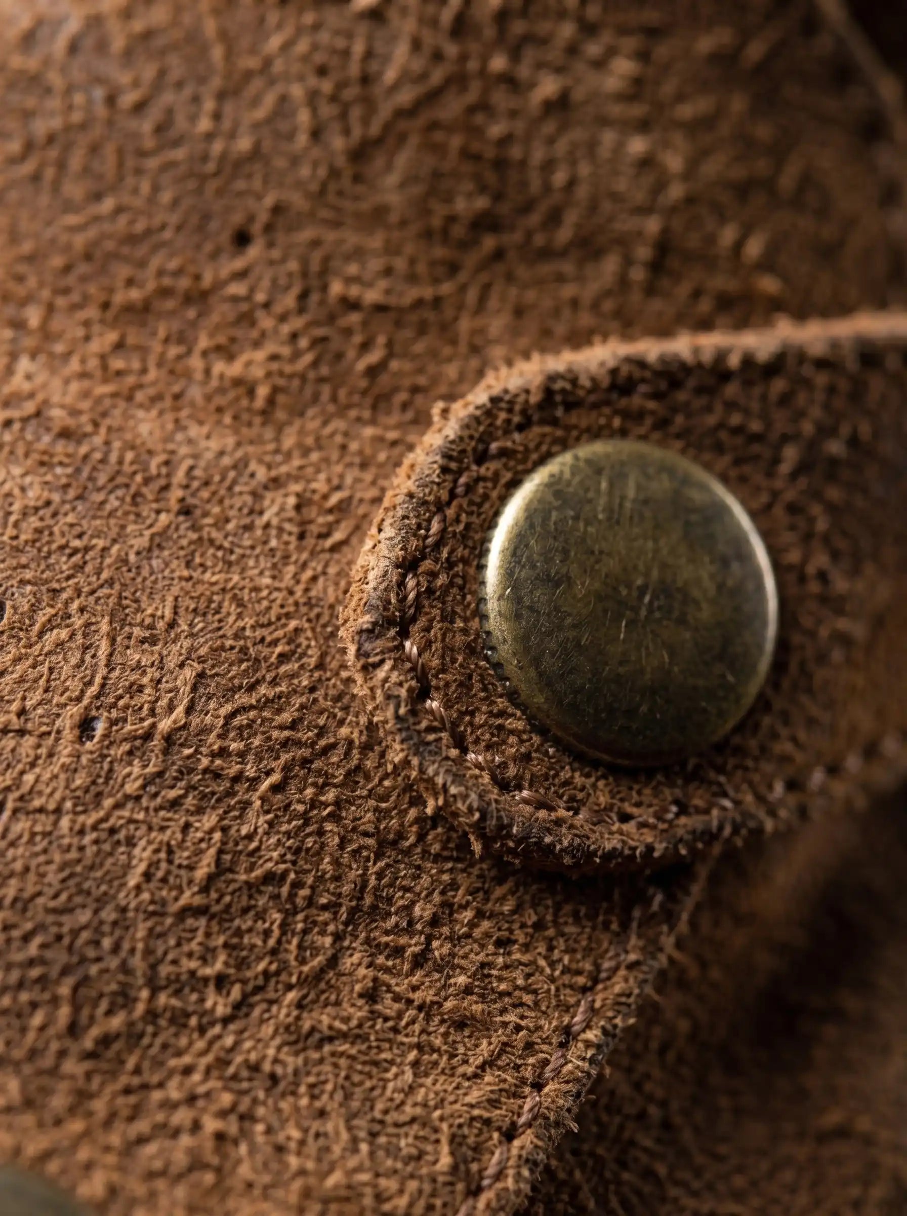 Antique brass snap button on inside of Noirtide Flynn Rider boot shaft — double-sided closure detail, brown leather